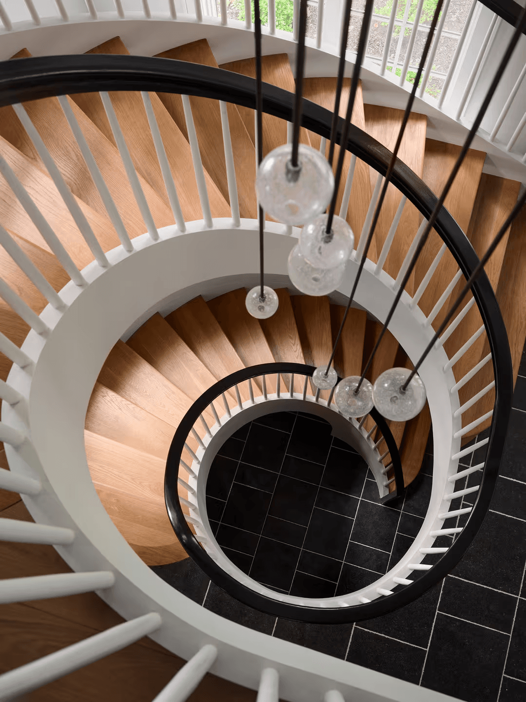 Overhead view of spiral staircase with glass pendant lights, Long Island residence