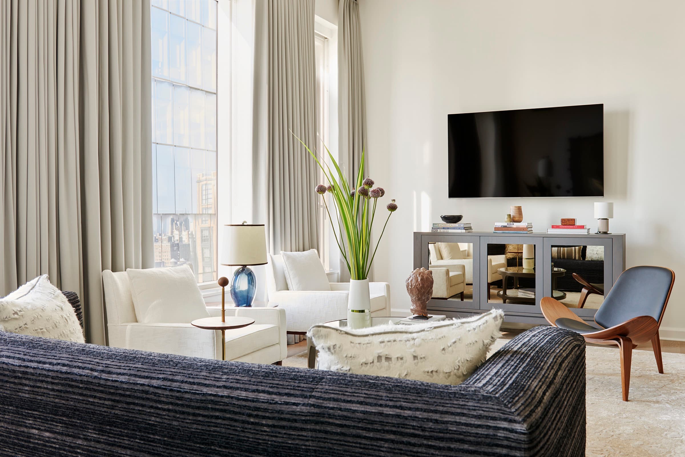 Vintage seating, sculptural lighting, and layered textures bring intimacy to the city view.